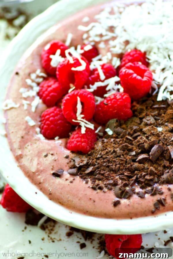 Close-up of a vibrant pink raspberry dark chocolate smoothie bowl with generous toppings