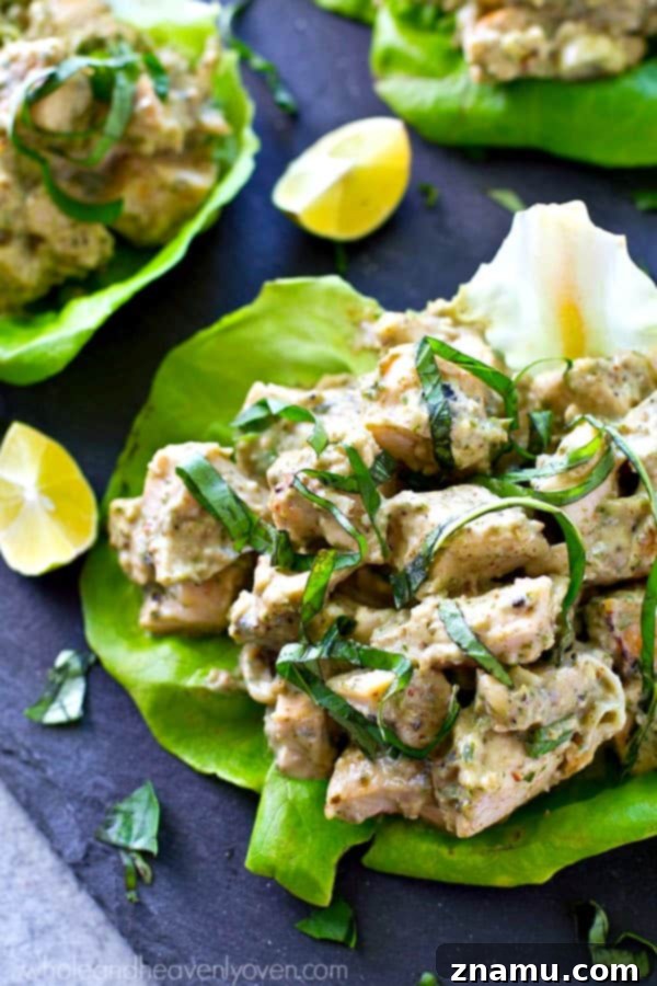 Pesto Grilled Chicken Lettuce Wraps 3 Close-up of a vibrant grilled chicken pesto lettuce wrap on a wooden board.