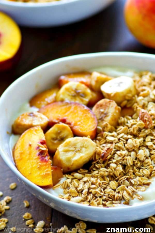A close-up of a spoon digging into a granola yogurt bowl, showing the delicious layers.