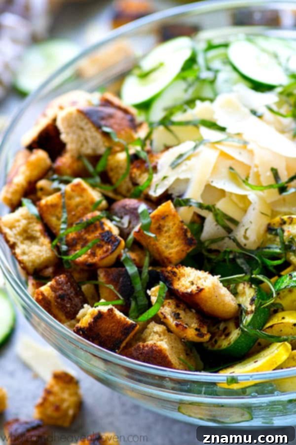 Grilled Summer Panzanella 3 Close-up view of the ingredients for Grilled Garden-Style Panzanella Salad, featuring freshly sliced zucchini, yellow squash, and crusty bread cubes ready for grilling, alongside colorful heirloom tomatoes and crisp romaine lettuce.