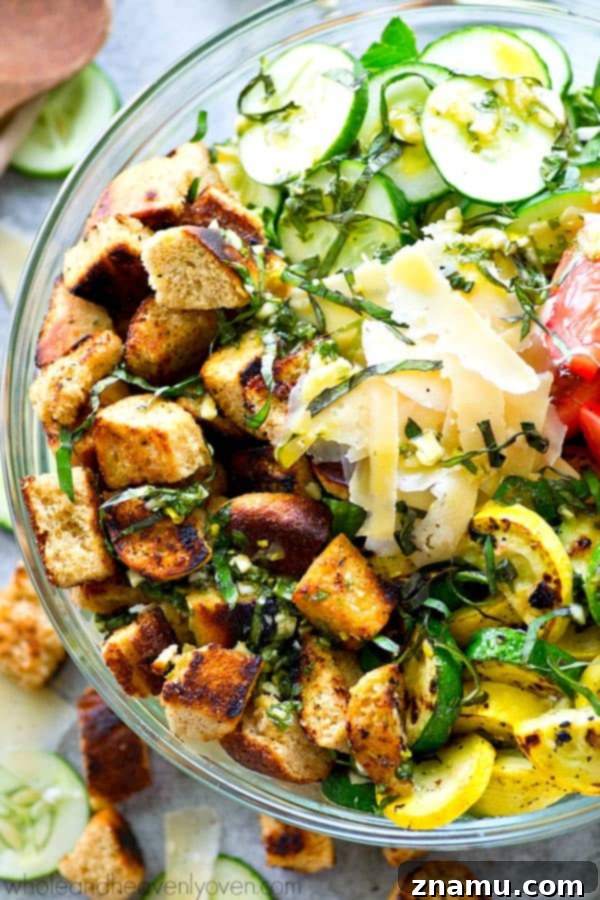 Grilled Summer Panzanella 4 A large, rustic wooden bowl filled with a bountiful Grilled Garden-Style Panzanella Salad, featuring charred zucchini and squash, juicy tomatoes, fresh basil, and perfectly grilled bread pieces. Parmesan shavings add a final touch.