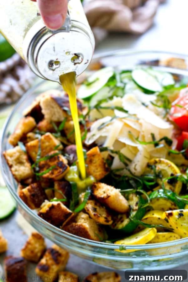 Grilled Summer Panzanella 6 A close-up view of the zesty herby vinaigrette being drizzled over the Grilled Garden-Style Panzanella Salad, highlighting the fresh basil and smooth texture of the dressing as it coats the vegetables and croutons.