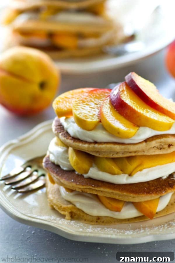 Peaches 'n' Cream Cheesecake Pancake Stacks 2 A towering stack of Peaches 'n' Cream Cheesecake Pancakes, showcasing golden-brown pancakes, creamy filling, and vibrant peach slices, perfect for summer brunch.