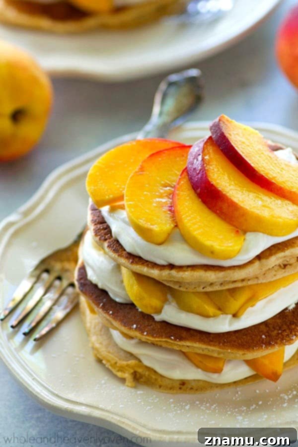 Peaches 'n' Cream Cheesecake Pancake Stacks 4 Peaches 'n' Cream Cheesecake Pancake Stack being drizzled with syrup, with soft pancakes and juicy peaches visible.