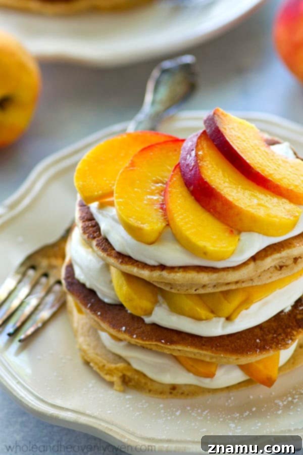 Peaches 'n' Cream Cheesecake Pancake Stacks 6 An appetizing close-up of a Peaches 'n' Cream Cheesecake Pancake Stack, highlighting the moist pancakes and generous layers of cream cheese and peaches.