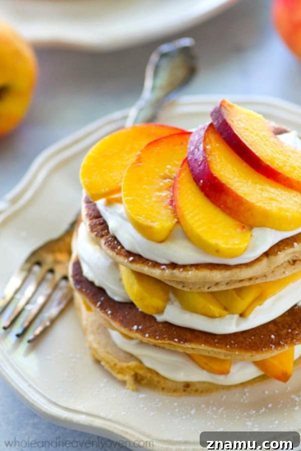Peaches 'n' Cream Cheesecake Pancake Stacks 7 Side view of multiple Peaches 'n' Cream Cheesecake Pancake Stacks garnished with powdered sugar, ready to be served.