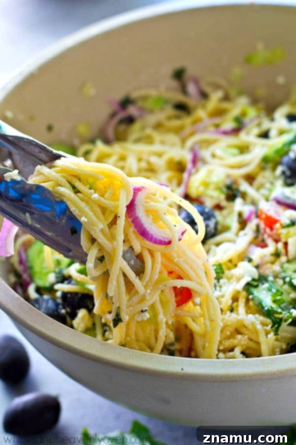 Mediterranean Spaghetti Toss with Zesty Dijon-Parmesan 7 A close-up shot of Greek Spaghetti Pasta Salad in a bowl, showing a fork ready to scoop.