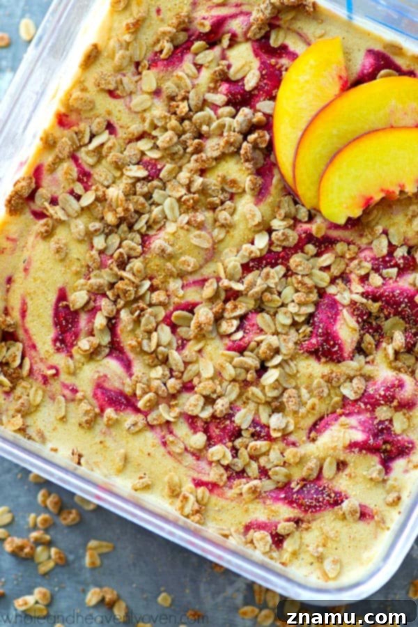Golden Peach Crumble & Raspberry Ripple Ice Cream 3 A close-up of a single scoop of peach raspberry swirl ice cream with visible streusel pieces, showcasing its creamy texture and vibrant colors