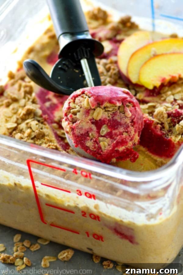 Golden Peach Crumble & Raspberry Ripple Ice Cream 4 A beautifully composed shot of multiple scoops of homemade peach crisp raspberry swirl ice cream in a bowl, highlighting the layers of flavor