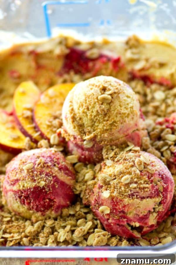 Golden Peach Crumble & Raspberry Ripple Ice Cream 7 Several scoops of peach crisp raspberry swirl ice cream in a rustic bowl, garnished with extra streusel and fresh raspberries
