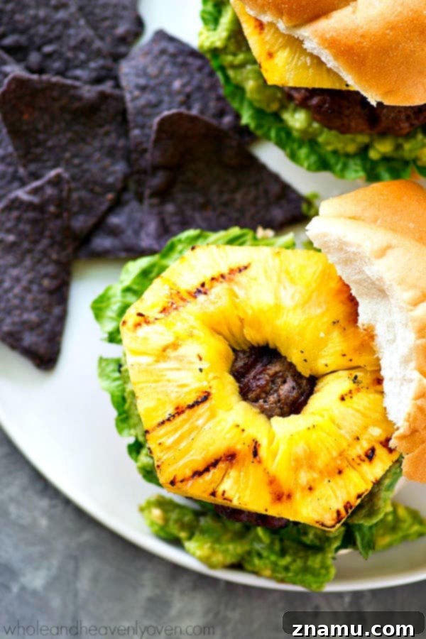 Jerk-Grilled Hamburgers with Avocado and Grilled Pineapple 3 Close-up of a juicy jerk burger with avocado and grilled pineapple on a toasted bun