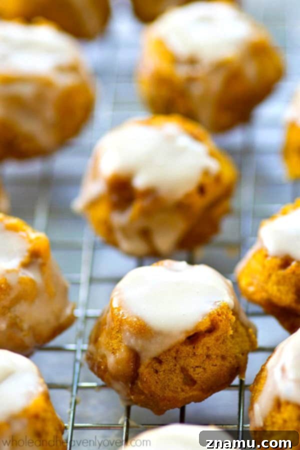 Lighter Pumpkin Spice Glaze Poppers 5 Close-up of a pumpkin spice donut hole coated in creamy vanilla glaze.