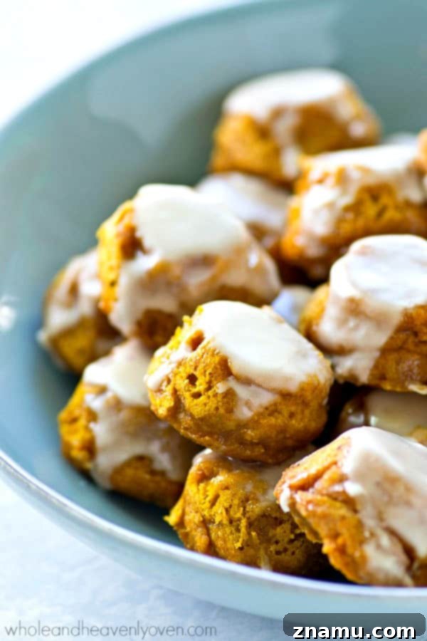 Lighter Pumpkin Spice Glaze Poppers 7 A pile of healthy glazed pumpkin spice donut holes on a rustic wooden board.