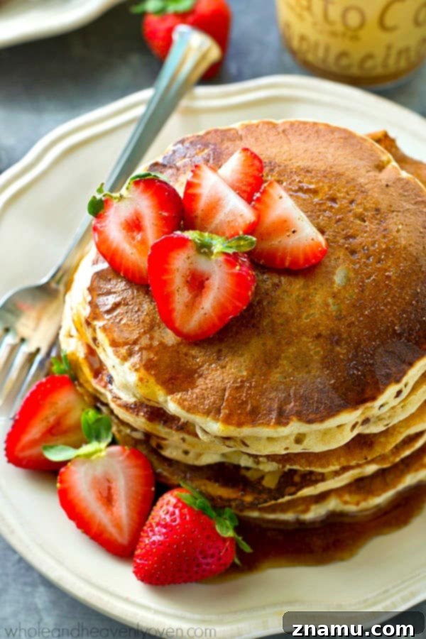 Chai Maple Drizzled Protein Power Pancakes 3 Close-up shot of a stack of fluffy protein pancakes with a rich, golden-brown exterior, hinting at the delightful texture within, garnished with berries.