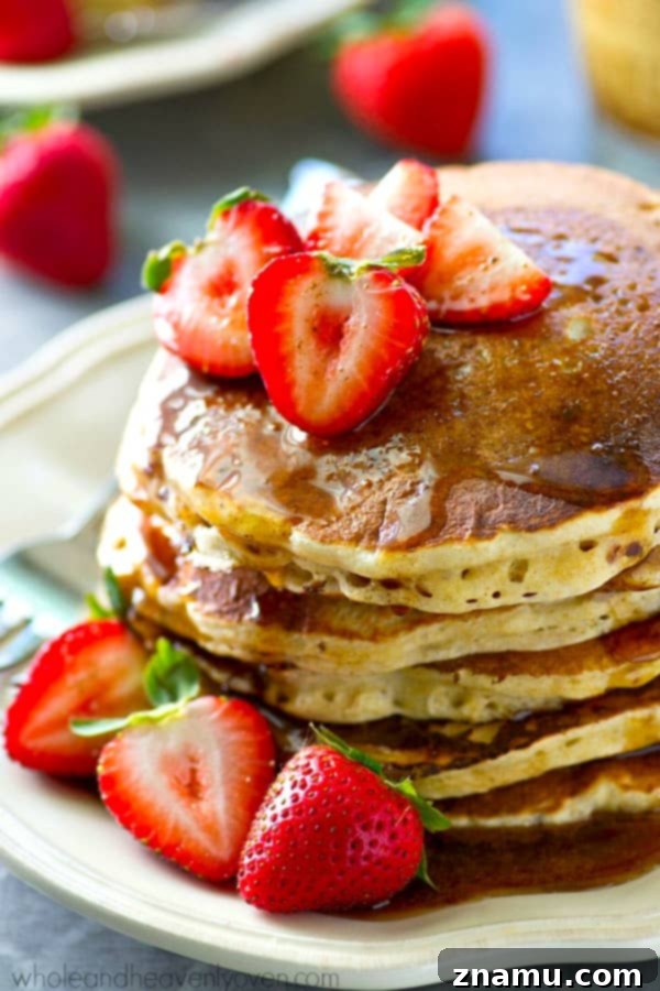 Chai Maple Drizzled Protein Power Pancakes 4 A close-up view of the ingredients for protein power pancakes, including a bowl of mashed banana, a scoop of vanilla protein powder, and Greek yogurt.