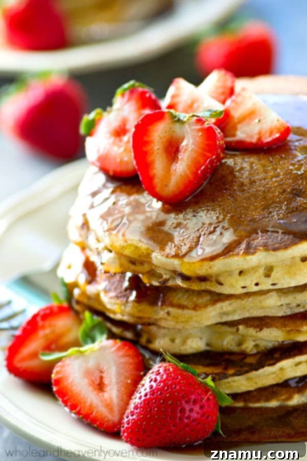 Chai Maple Drizzled Protein Power Pancakes 8 A fork piercing a stack of protein power pancakes, revealing their tender interior, ready to be enjoyed.