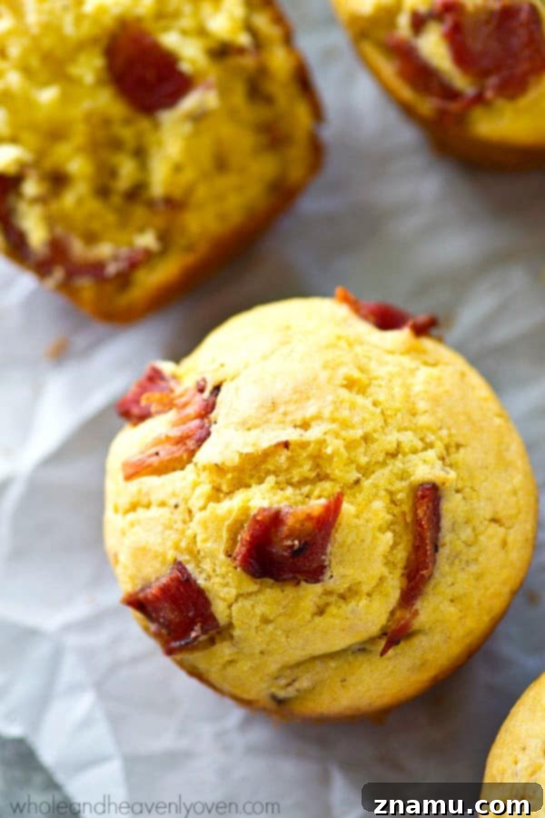 Brown Butter Bacon Cornbread Muffins 3 A close-up of golden-brown cornbread muffins with visible crispy bacon pieces and a hint of browned butter.