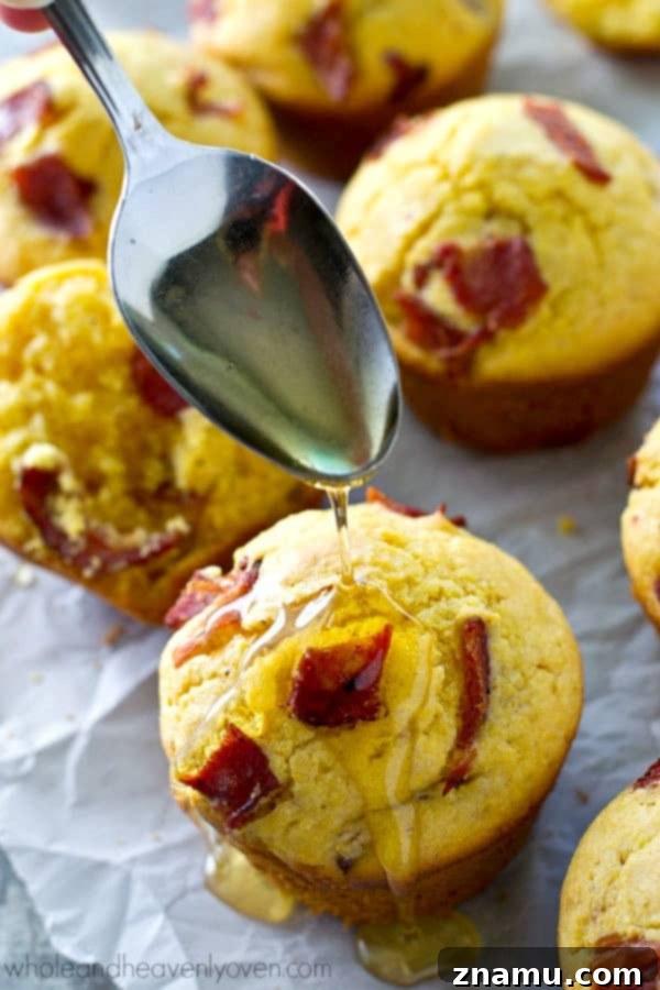 Brown Butter Bacon Cornbread Muffins 7 A pair of freshly baked browned butter bacon cornbread muffins, one broken open to showcase its tender, flavorful interior.