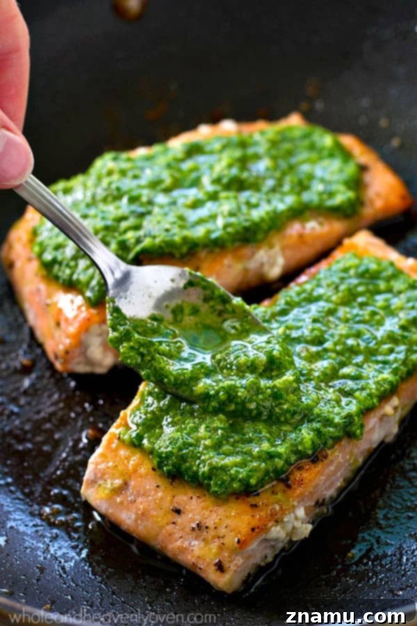 Perfectly Seared Salmon with Spinach Basil Pesto 2 Perfectly pan-seared salmon fillets topped with fresh spinach basil pesto, ready to serve for a quick and healthy meal.