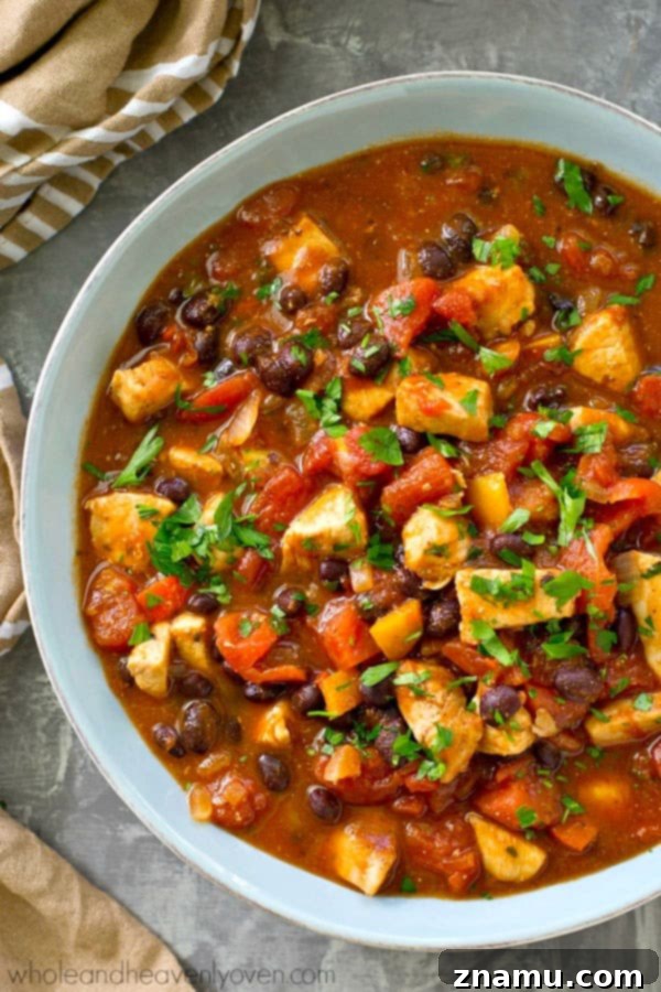 Smoky Hearty Slow Cooker Chipotle Chicken Chili 2 A steaming bowl of hearty crockpot chipotle chicken chili, garnished with fresh cilantro and a dollop of sour cream, ready for a football party.