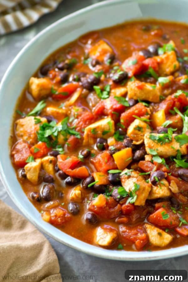 Smoky Hearty Slow Cooker Chipotle Chicken Chili 6 The finished chipotle chicken chili in a bowl, topped with a generous sprinkle of fresh parsley, showcasing its rich texture and vibrant colors.