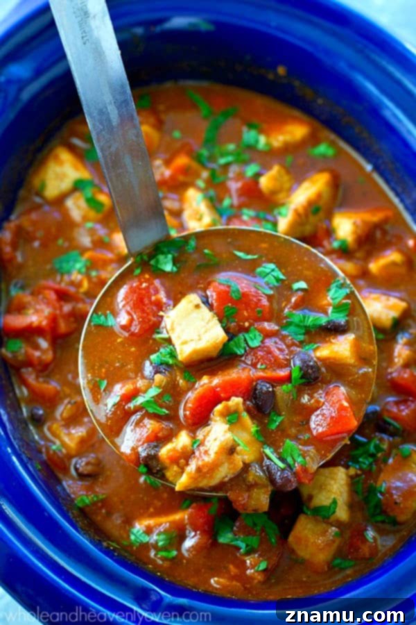 Smoky Hearty Slow Cooker Chipotle Chicken Chili 7 A beautifully composed shot featuring a bowl of chipotle chicken chili with a side of golden-brown cornbread muffins, ready to be enjoyed.