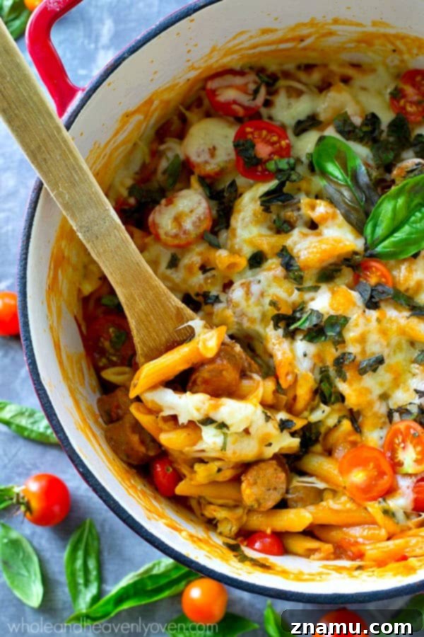 Basil Sausage Caprese Skillet Pasta 5 A close-up view of the ingredients for one-pot caprese pasta, including sliced chicken sausage, penne pasta, and fresh basil.