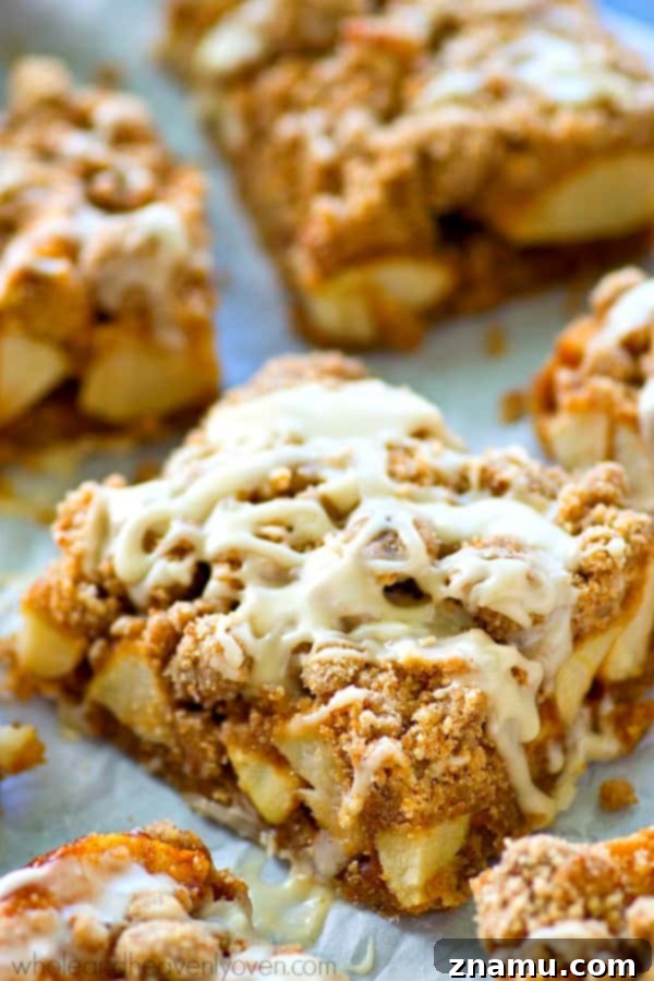 Apple Streusel Bars with Vanilla Glaze 7 Hand reaching for a piece of freshly glazed Glazed Apple Pie Crumb Bar