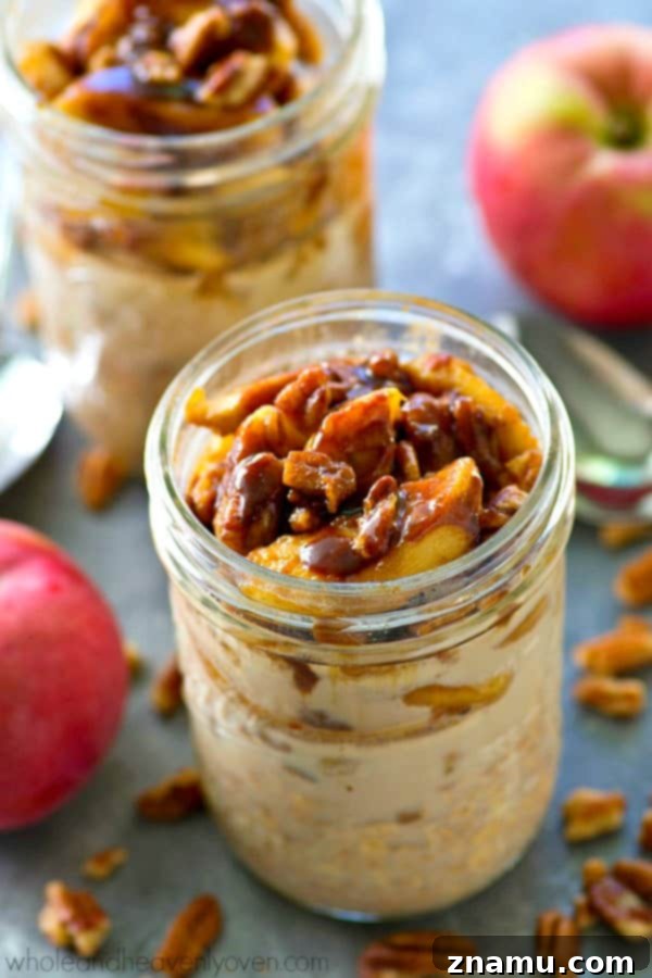 Close-up of a spoon digging into Caramelized Apple Cinnamon Roll Overnight Oats, showing the layers of oats and apples.