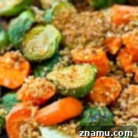Irresistible Roasted Brussels Sprouts and Carrots for Thanksgiving A close-up shot of perfectly roasted Brussels sprouts and carrots, generously coated with a savory Parmesan panko crust, served in a rustic bowl.