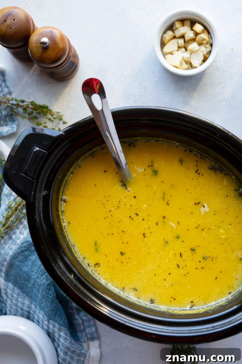 Creamy Crockpot Butternut Squash Soup 4 A vibrant bowl of butternut squash soup, highlighting its rich orange color and creamy consistency, garnished with fresh thyme leaves.