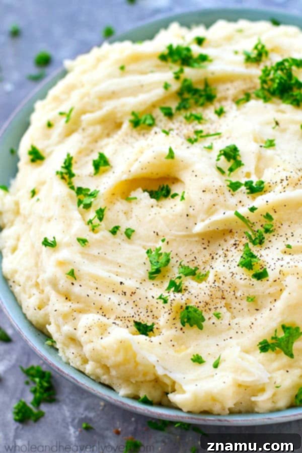 The Ultimate Creamy Garlic Whipped Potatoes 3 A serving of garlic whipped mashed potatoes, showcasing their smooth texture and garnished with a sprinkle of fresh parsley, ideal for holiday meals.