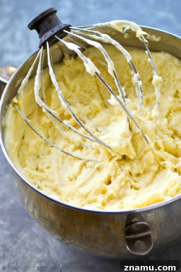 The Ultimate Creamy Garlic Whipped Potatoes 6 A side view of a bowl of creamy mashed potatoes with melted butter, showcasing the smooth, velvety consistency achieved through whipping.