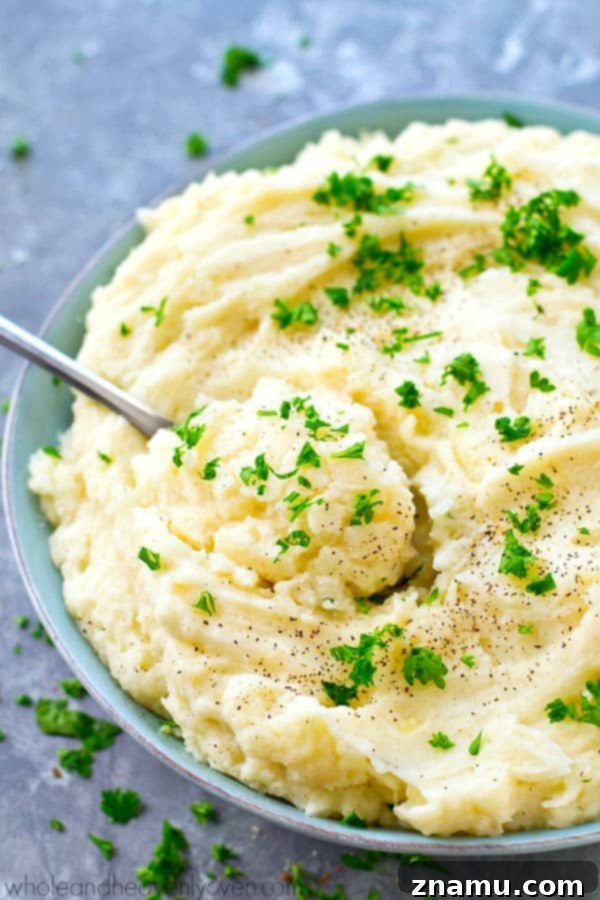 The Ultimate Creamy Garlic Whipped Potatoes 7 A bowl of garlic whipped mashed potatoes ready for serving, garnished with parsley, alongside a full Thanksgiving spread, emphasizing their place at the holiday table.