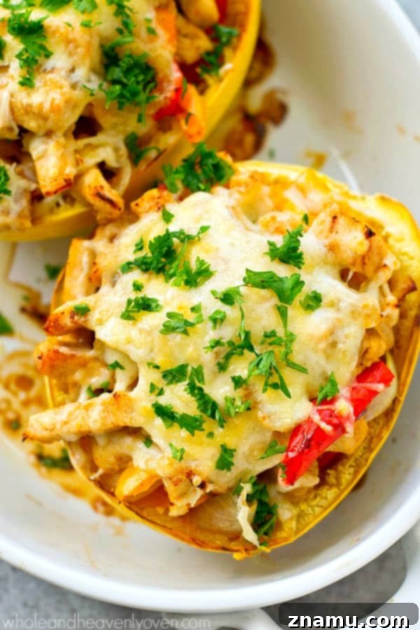 Close-up of a chicken fajita spaghetti squash boat displaying a rich filling of chicken, peppers, and onions under a blanket of melted cheese
