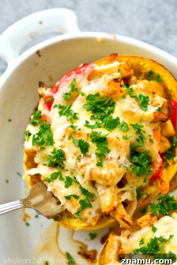A fork pulling a long, satisfying strand of melted mozzarella cheese from a chicken fajita spaghetti squash boat, enticingly gooey