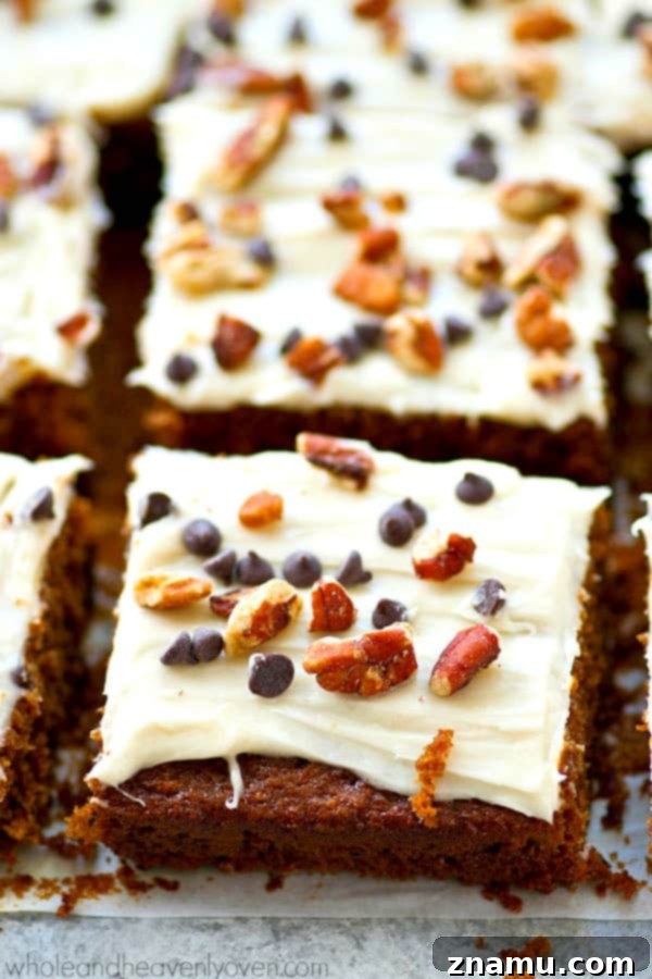 Close-up of fluffy gingerbread cake bars topped with creamy frosting and chocolate chips for a delicious holiday treat.