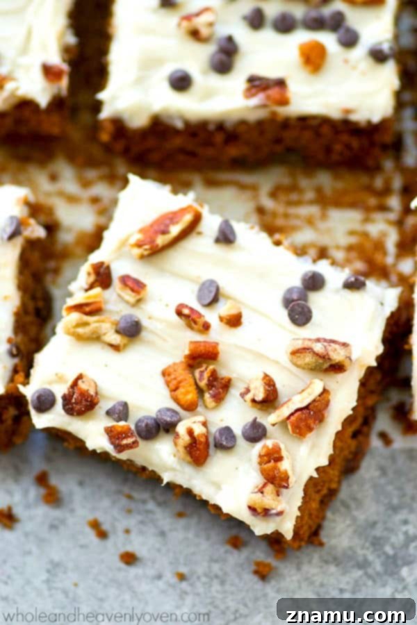 Gingerbread cake bars with chocolate chips and cream cheese frosting, garnished with more chocolate chips and pecans.