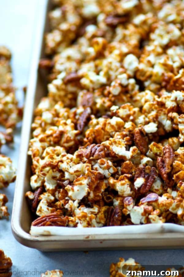 Pecan Praline Cinnamon Popcorn 3 Close-up of golden caramel popcorn with visible pecans and cinnamon, showcasing its irresistible texture