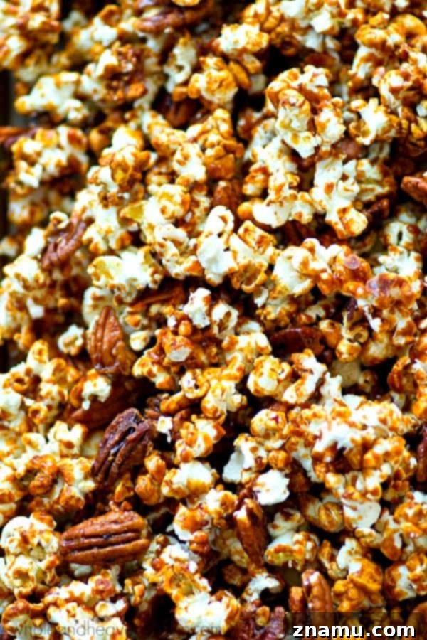 Pecan Praline Cinnamon Popcorn 4 Freshly made caramel popcorn with pecans and a sprinkle of cinnamon, cooling on a baking sheet