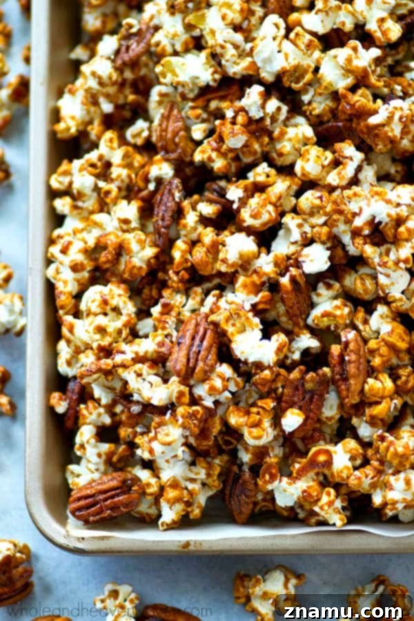 Pecan Praline Cinnamon Popcorn 6 Hand reaching for a piece of the freshly made caramel popcorn, highlighting its irresistible nature