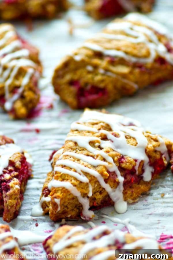 Sweet Glazed Raspberry Eggnog Scone Bites 7 A close-up shot of the finished mini eggnog scones, glistening with glaze and adorned with raspberries, highlighting their readiness to be enjoyed.