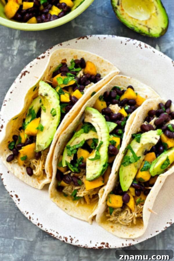 Easy Crockpot Green Chile Chicken Tacos with Fresh Mango Black Bean Salsa 7 Close-up of a single Crockpot Green Chile Chicken Taco topped with mango salsa