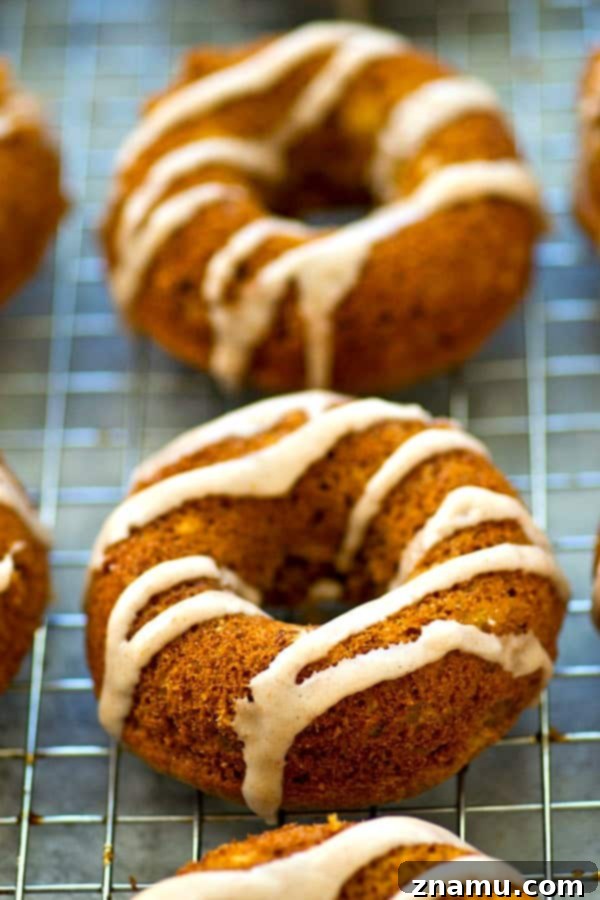 A hand drizzling spicy chai glaze over a baked banana bread donut.