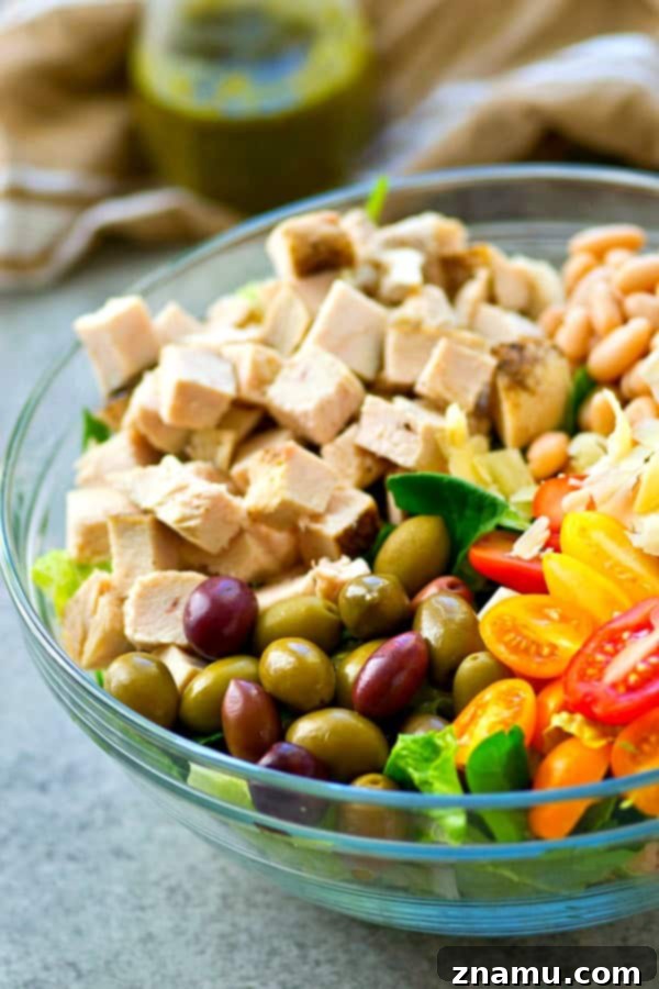 A Taste of Tuscany: Turkey & Pesto Salad 3 A vibrant and generously portioned Tuscan turkey salad, showcasing an abundance of fresh ingredients like greens, turkey, beans, and tomatoes.
