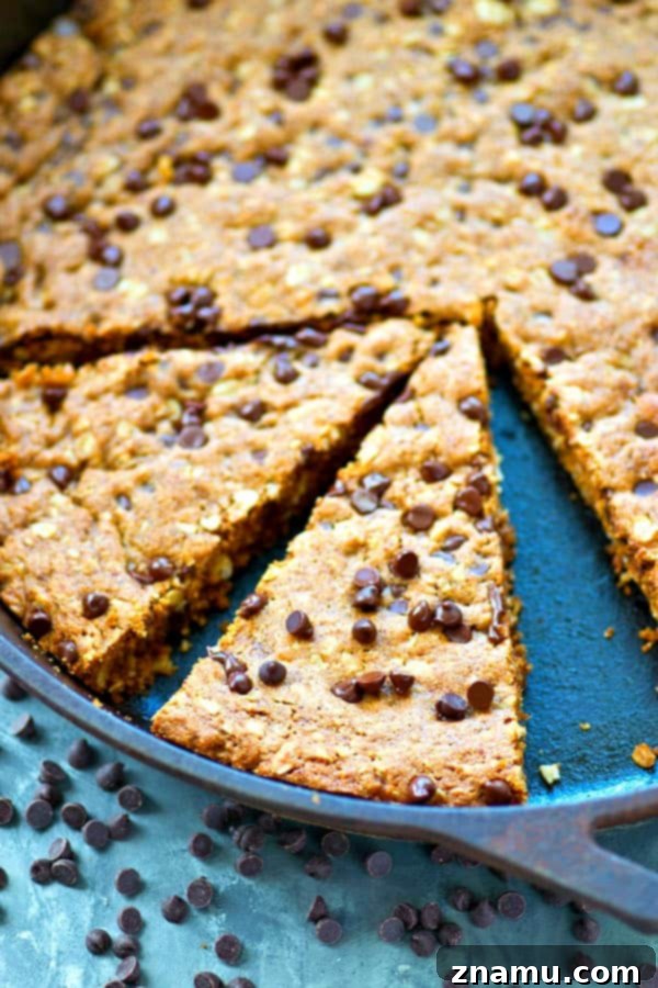 Hindistan Cevizi Yağı, Yulaf ve Damla Çikolatalı Tava Kurabiyesi 4 A large, round oatmeal chocolate chip skillet cookie with melted chocolate, showcasing its soft and chewy texture.