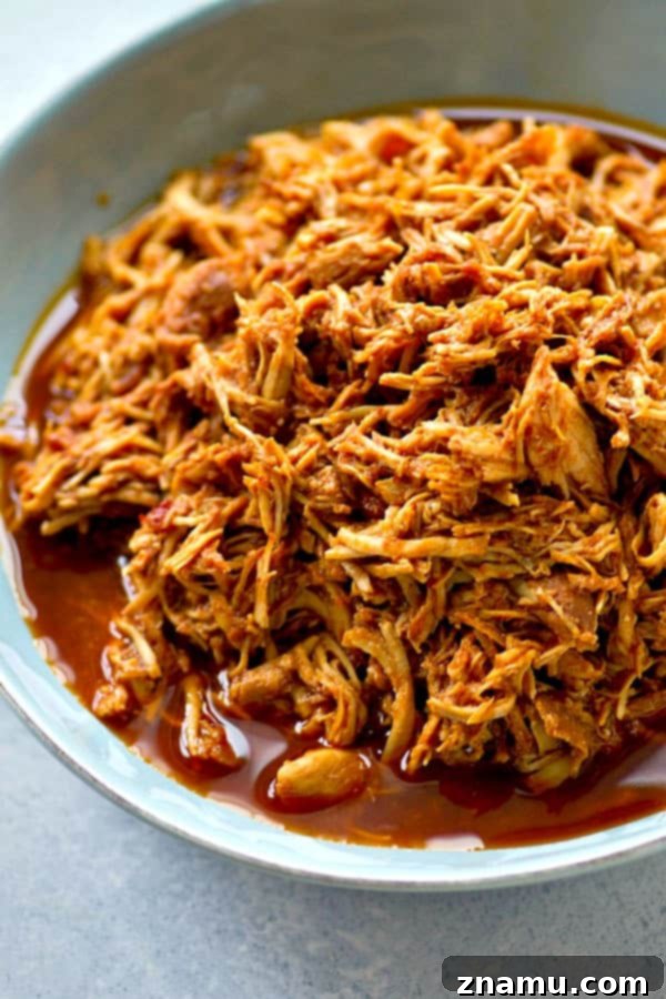 Sweet and Smoky Crockpot Chipotle Maple BBQ Chicken Sandwiches 3 Close-up of succulent shredded chicken coated in chipotle maple BBQ sauce, ready to be served from a slow cooker.
