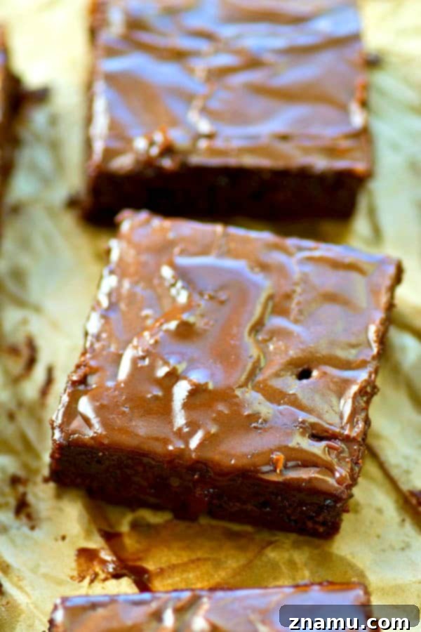 A stack of freshly baked, moist brownies with a glossy mocha glaze, ready to be enjoyed.