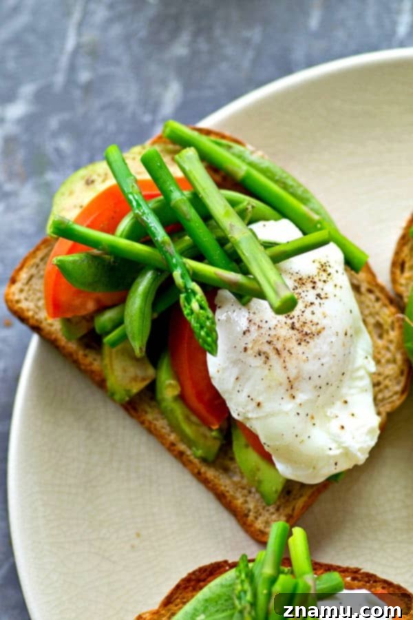 Spring Avocado Toast Delights 6 Finished Spring Avocado Toast artfully arranged with asparagus, tomatoes, sugar snap peas, and a poached egg