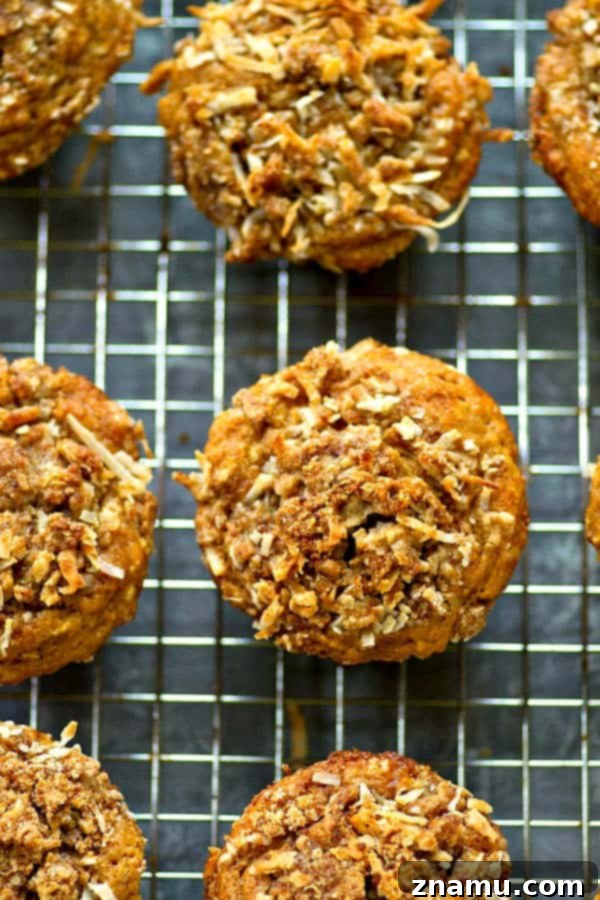 A stack of golden-brown banana coconut streusel muffins, with flaky coconut visible in the streusel.